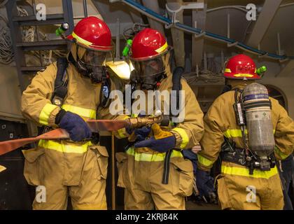 221118-N-TT639-1013 OCEANO PACIFICO (18 novembre 2022) – i marinai fingono una manichetta antincendio durante una perforazione generale a bordo di un carrier d'assalto anfibio USS Tripoli (LHA 7) 18 novembre 2022. Tripoli sta conducendo operazioni di routine nella U.S. 3rd Fleet. Foto Stock