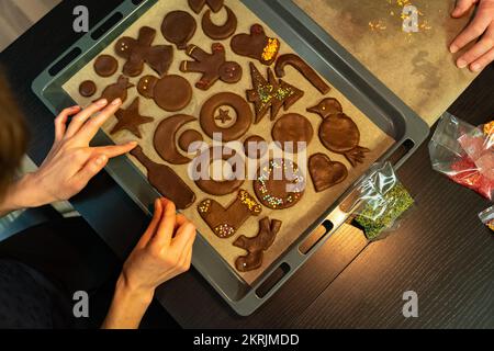 Vista dall'alto di una teglia da forno con biscotti di pan di zenzero di forme diverse durante la decorazione Foto Stock