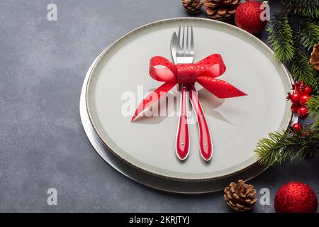 Tavolo di Natale composto da un piatto e posate legate con un arco. Vista laterale Foto Stock