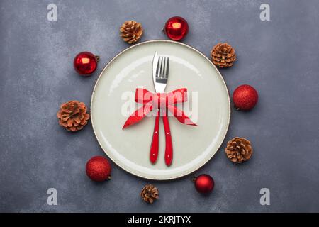 Tavolo di Natale composto da un piatto e posate legate con un arco. Giacitura piatta Foto Stock