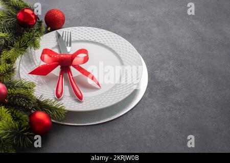 Tavolo di Natale composto da un piatto bianco e posate legate con un arco. Vista laterale con spazio di copia Foto Stock
