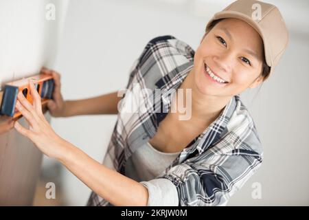 donna che sorride alla macchina fotografica mentre tiene un livello di sprit Foto Stock