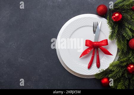 Tavolo di Natale composto da un piatto bianco e posate legate con un arco. Vista dall'alto con spazio di copia Foto Stock