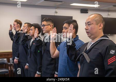 I marinai e i familiari con sede a Sasebo si impegnano a dare il giuramento di naturalizzazione di Allegiance agli Stati Uniti d'America durante una cerimonia di naturalizzazione al Comandante, Fleet Activities Sasebo 21 novembre 2022. STATI UNITI Citizenship and Immigration Services and Region Legal Service Office Western Pacific ha collaborato per condurre la cerimonia di naturalizzazione al CFAS consentendo ai marinai di diventare cittadini degli Stati Uniti. Foto Stock