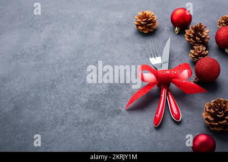 Set tavola di Natale composto da posate, coltello e forchetta legati con un arco rosso Foto Stock