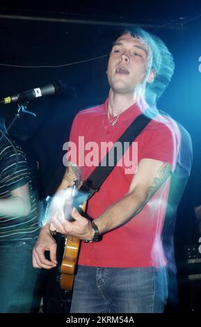 SAMUEL PRESTON, THE ORDINARY BOYS, 2004: Un giovane Samuel Preston in rosso, cantante e chitarrista dei The Ordinary Boys al Welsh Club di Cardiff, Galles, Regno Unito, il 19 ottobre 2004. Fotografia: ROB WATKINS. INFO: The Ordinary Boys sono un gruppo musicale indie rock britannico formatosi nel 2002 a Worthing. Noti per il loro suono energico e i testi socialmente consapevoli, hanno guadagnato fama con il loro album di debutto "Over the Counter Culture" e successi come "Boys Will Be Boys". Foto Stock