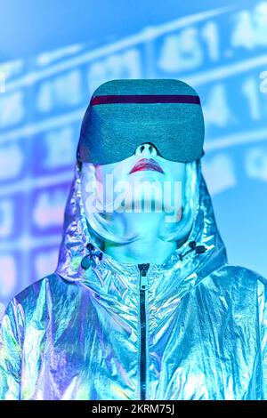 Giovane donna bionda in VR cuffie in piedi contro il muro con numeri al neon incandescente su immagine irrealistica ammirando Foto Stock
