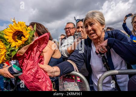 Una donna anziana passa Un mazzo di fiori a Un ufficiale di polizia per mettere fuori dai cancelli di Buckingham Palace dopo la morte della Regina, Londra, Regno Unito Foto Stock