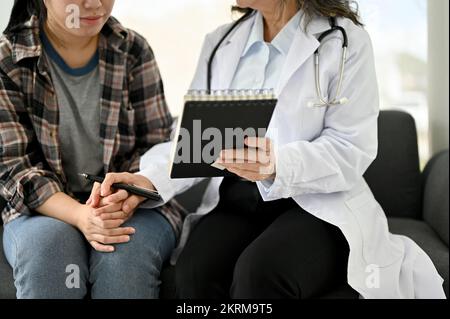 Medico di età asiatica professionista ha spiegato il piano di trattamento al suo paziente durante la consulenza. immagine ritagliata Foto Stock