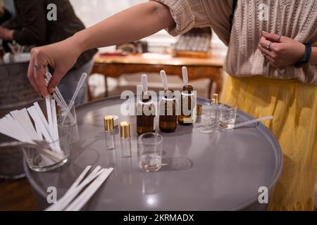 Artigiano anonimo corto con contagocce che fanno profumo in vaso di vetro sul tavolo a casa Foto Stock