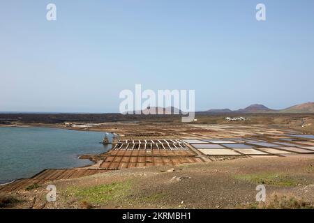 Panorama mozzafiato di saline in terreno vulcanico vicino all'oceano contro cielo blu nuvoloso a Salinas de Janubio a Las Palmas nelle giornate di sole Foto Stock