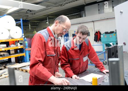 Formazione professionale nella costruzione di metalli - apprendista e lavoratore qualificato che parla e impara - carriere per i giovani del settore Foto Stock