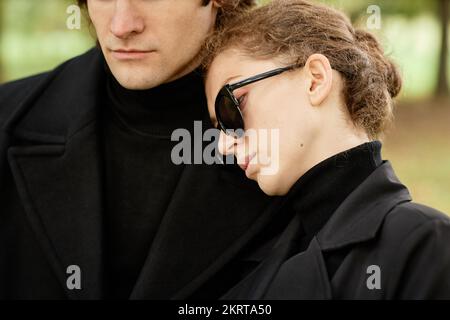 Primo piano della giovane donna che appoggia la mano sulla spalla dei mariti mentre dice Arrivederci alla cerimonia funeraria all'aperto Foto Stock