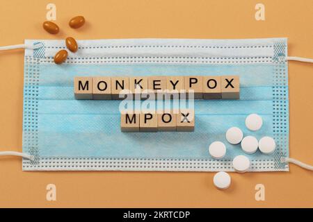 MPOX è il nuovo nome per il virus monkeypox. Le parole sono disposte con cubi di legno su una maschera chirurgica. Foto Stock