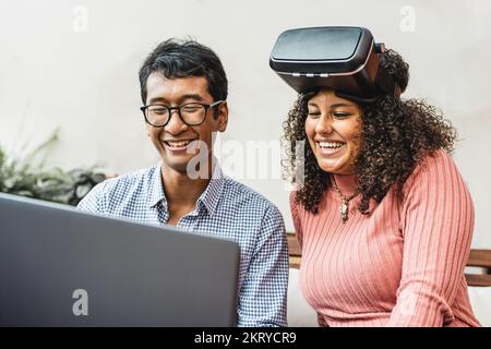 i giovani di generazione z utilizzano la realtà aumentata, due persone biraciali che guardano lo schermo del notebook per vivere l'esperienza nella realtà virtuale e nel metaverse Foto Stock