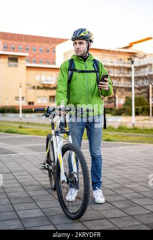 Addetto alla consegna in cerca di indirizzo, giovane pilota che utilizza l'applicazione mobile e la mappa della città per la ricerca del cliente, ecologico veloce corriere nuovo business Foto Stock