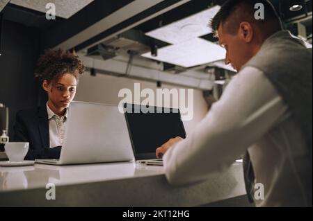 Donna e uomo che scrivono sul notebook seduto in ufficio Foto Stock