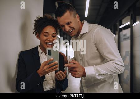 Donna e uomo ridenti che guardano lo schermo dello smartphone Foto Stock