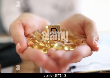 Primo piano delle mani di una donna che tiene molte capsule di vitamina D. Foto Stock