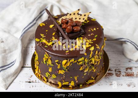 Pistacchio e torta al cioccolato. Torta di compleanno o di celebrazione su uno sfondo di legno bianco. primo piano Foto Stock