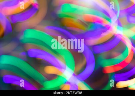 Strisce di luce diagonali al neon multicolore luminose e luminose, simili alle molle come lo sfondo o le carte da parati. Disegno astratto. Effetto fotografico di mo Foto Stock