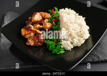 Pollo Kung Pao con sugo di carne. Cibo asiatico su sfondo nero. Foto Stock