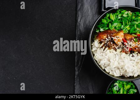 terrina di riso al pollo teriyaki - stile asiatico. Cibo asiatico. Cibo tailandese. Riso con pollo e cipolle verdi su fondo scuro. Cibo cinese. Foto Stock