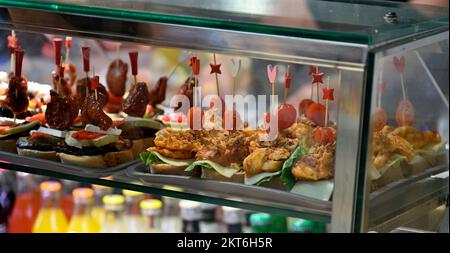 Mostra di piccoli spuntini, 'pinchos', in un tapas cafe all'interno del Mercado del Puerto, il mercato sul porto Foto Stock