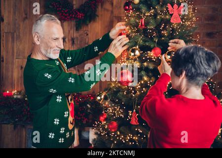 Foto di due persone allegre e pacifiche che appendono giocattoli albero di nuovo godere di festa magia tempo al coperto Foto Stock