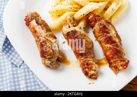 Truppa di maiale al forno con pasta di penne. Ricetta della cucina italiana. Foto Stock