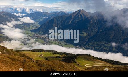 Paesaggio alpino autunnale con vista panoramica sulle montagne, cielo nuvoloso e un insediamento nella valle. Austria, Salisburgo, Valle di Gastein. Alta qua Foto Stock