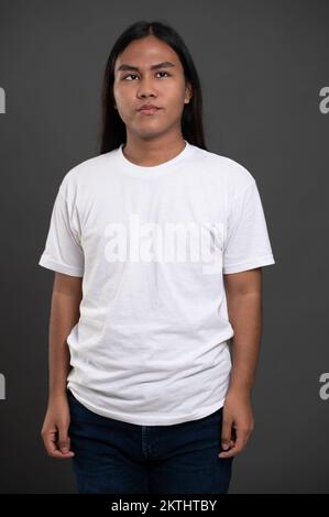 Ritratto di un ragazzo con capelli lunghi isolato su sfondo grigio studio Foto Stock