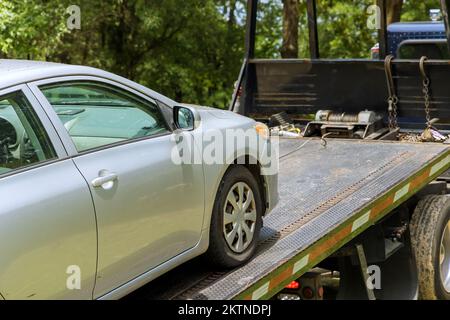 Processo di caricamento di una vettura danneggiata o rotta sul carrello di traino che lavora in una società di traino Foto Stock