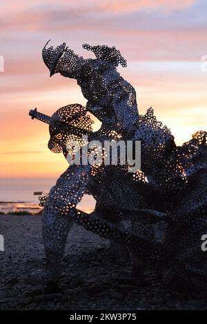 Figura scultorea a grandezza naturale nel giardino D-Day 75 a Arromanches-les-Bains, Francia al tramonto. L'installazione è stata creata per la prima volta da John Everiss for Foto Stock