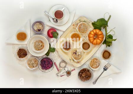 Una varietà di piccole mini torte per il giorno del Ringraziamento e l'autunno -- mela, bacche, pesca, pecan, zucca, patata dolce -- su un tavolo con tovaglia bianca, top Foto Stock