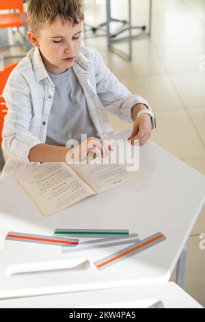 Khabarovsk, Russia, 28 ottobre 2022. Bambino dislessico lettura libro dislessia striscia righello colore Foto Stock