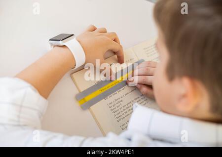 Khabarovsk, Russia, 28 ottobre 2022. Bambino dislessico lettura libro dislessia striscia righello colore Foto Stock