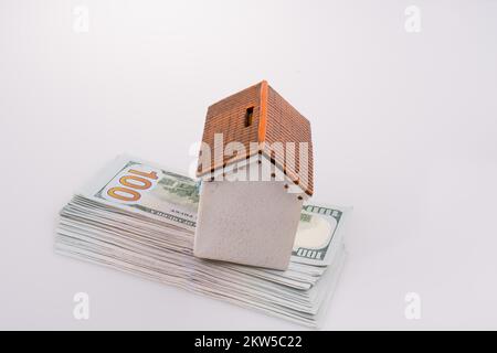 Modello di casa collocata sul dollaro americano banconote su sfondo bianco Foto Stock