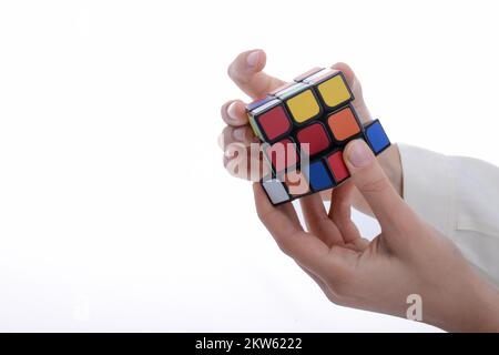 Bambino tenendo un cubo di Rubik in mano su uno sfondo bianco Foto Stock