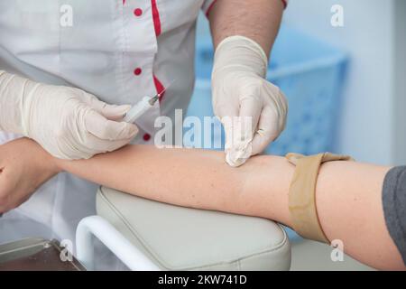 La mano ravvicinata di un'infermiera, un medico o un tecnico medico in guanti medici preleva un campione di sangue da un paziente in ospedale. Foto Stock