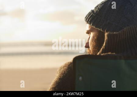 Vista sull'oceano. Vista sulla spalla di un uomo seduto sulla spiaggia. Foto Stock
