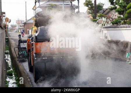 Rullo pneumatico di pneumatici che compattano nuovo asfalto di una strada. Rifare il manto stradale. Lavori stradali. Foto Stock