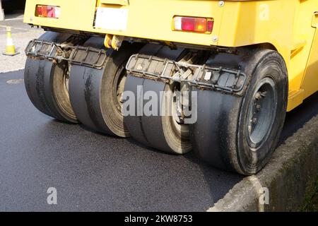 Rullo pneumatico di pneumatici che compattano nuovo asfalto di una strada. Rifare il manto stradale. Lavori stradali. Foto Stock