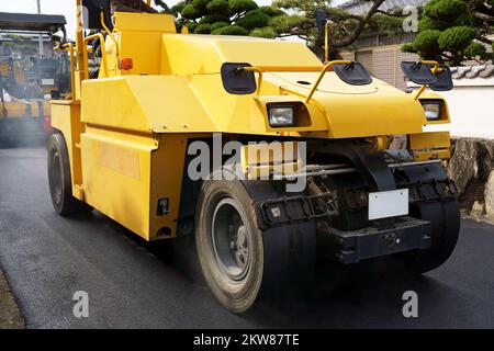 Rullo pneumatico di pneumatici che compattano nuovo asfalto di una strada. Rifare il manto stradale. Lavori stradali. Foto Stock