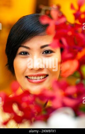 Receptionist vietnamita in posa per un ritratto indossando ao dai, ho Chi Minh City, Vietnam Foto Stock