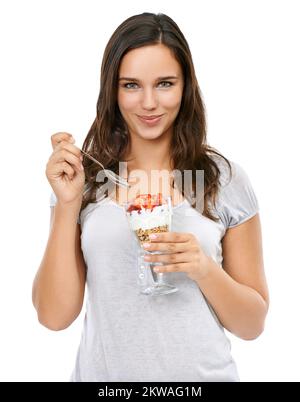 Il relativo COSÌ buon. Studio ritratto di una giovane donna che mangia una sana colazione. Foto Stock
