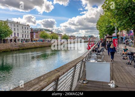 Bachelors Walk, una banchina sulla riva nord del fiume Liffey, con caffè marciapiede. Aston Quay e Ha'penny ponte sono sullo sfondo. Foto Stock