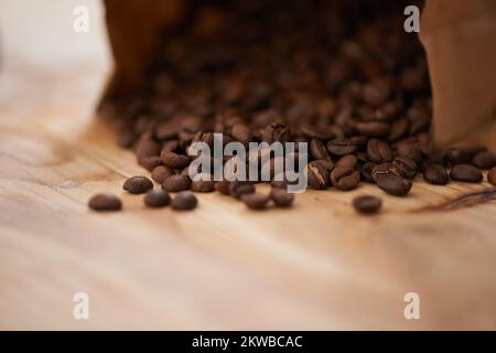 Le gioie del caffè fresco. chicchi di caffè arrostiti fuoriusciti da un sacchetto su un bancone. Foto Stock