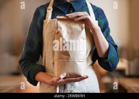 SA come preparare la migliore tazza di caffè. una donna che tiene una borsa mentre indossa un grembiule. Foto Stock