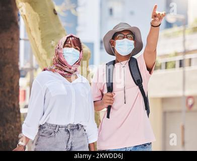 Covid, viaggi e turismo con una coppia musulmana che indica mentre visitano all'aperto all'estero o all'estero. Turista, maschera e luna di miele con un uomo islamico Foto Stock